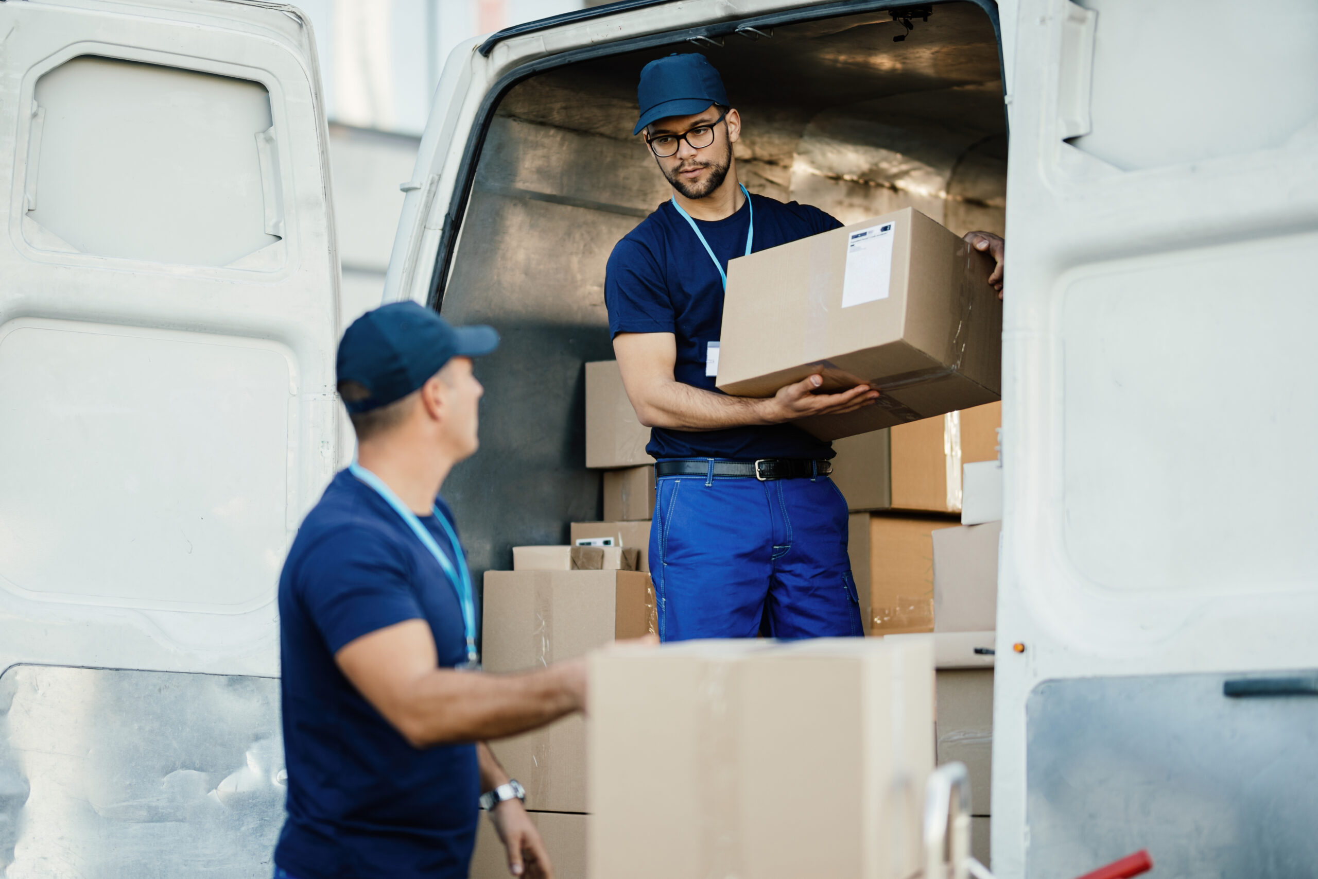 due lavoratori che caricano scatole di cartone su un furgone